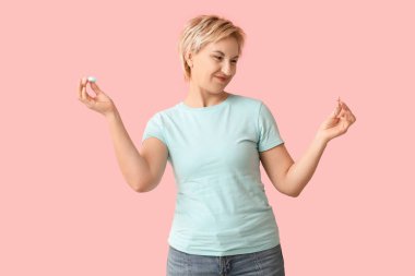 Lens kutusu ve pembe arka planda gözlüğü olan olgun bir kadın.