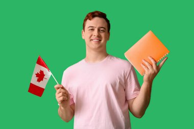 Kanada bayrağı ve yeşil arka planda not defteri olan bir erkek öğrenci.