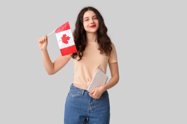 Kanada bayrağı ve gri arka planda not defteri olan bir kız öğrenci.