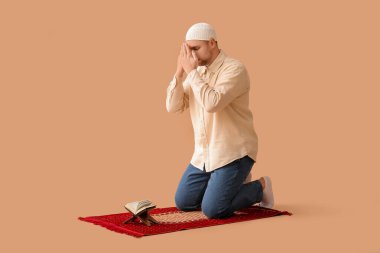 Paspaslı ve Kuran 'lı genç Müslüman adam bej arka planda dua ediyor.