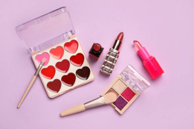 Eflatun arka planda dekoratif kozmetik seti. Üst görünüm