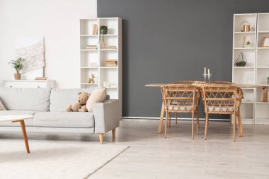 Gri kanepe, yemek masası ve raf üniteleriyle aydınlatma odasının içinde.