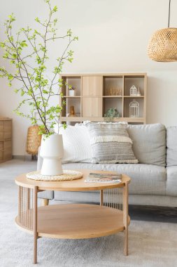 Şık oturma odasının içinde rahat bir kanepe, sehpa ve vazoda çiçek açan ağaç dalları var.