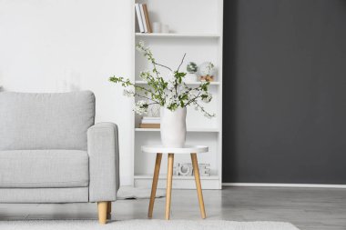 Beyaz oturma odasındaki sehpanın üzerinde çiçek açan bir vazo.