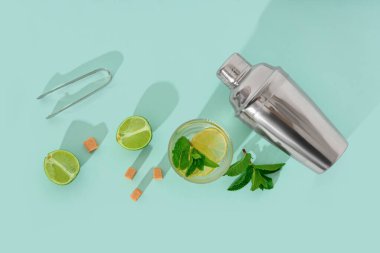 Bir bardak taze mojito. Kokteyl karıştırıcı ve mavi arka planda şeker.
