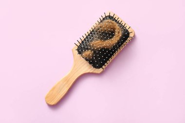 Leylak arka planında saç telinden yapılmış fırça ve soru işareti. Saç dökülme problemi