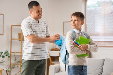 Küçük çocuk ve babası okul çantalarını sırt çantasına koyuyorlar.