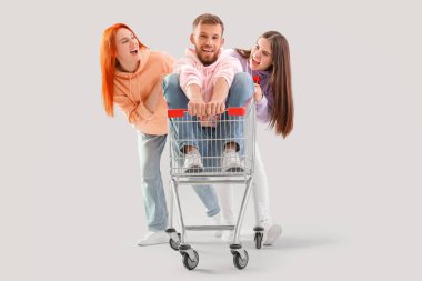 Arkadaşlarıyla alışveriş arabasındaki genç adam arka planda yarışıyor.