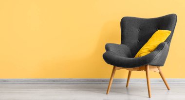 Sarı duvarın yanında yastıklı şık gri koltuk. Tasarım için pankart