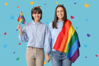 Açık mavi arka planda LGBT bayrakları olan genç lezbiyen çift