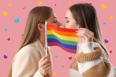 Genç lezbiyen çift pembe arka planda LGBT bayrağının arkasında öpüşüyor 