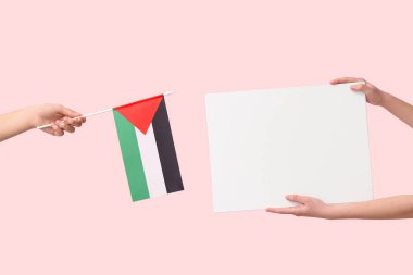 Filistin bayrağı taşıyan kadın eller ve pembe arka planda boş poster.