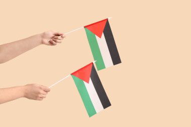Bej arka planda Filistin bayrakları olan kadın elleri
