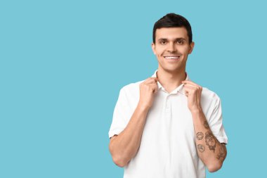 Mavi arka planda şık beyaz tişörtlü yakışıklı genç adam.