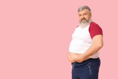 Pembe arka planda şişman, mutlu, olgun bir adam. Kilo verme konsepti