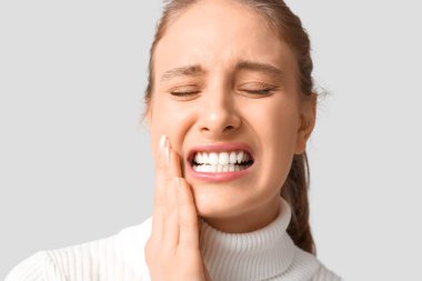 Gri arka plan üzerinde diş ağrısı muzdarip güzel genç kadın