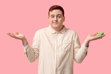 Pembe arka planda saç derisi masaj aleti olan genç bir adam.