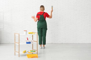 Işık odasında duvar boyayan kadın dekoratör.