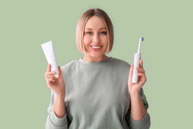 Yeşil arka planda diş fırçası ve yapıştırıcısı olan kadın