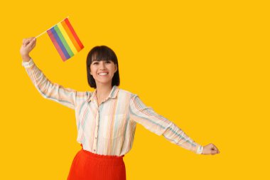 Sarı arka planda LGBT bayrağı olan güzel genç bir kadın.