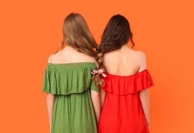 Turuncu arka planda örgülü saçları olan genç kız kardeşler.