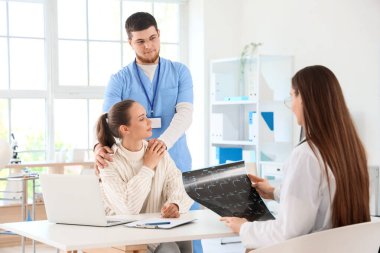 Doktorlar, klinikte omurga görüntüsü olan genç bir kadını sakinleştiriyor.