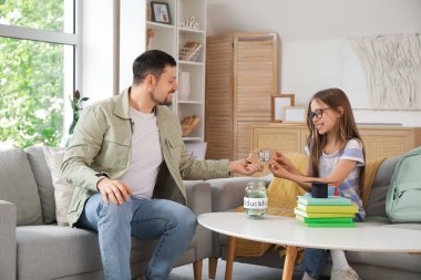 Babası ve kızı evde domuz kumbarası ve para kavanozuyla. Okul harcı konsepti