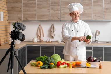 Taze sebzeli erkek şef mutfakta yemek pişirme videosu kaydediyor.