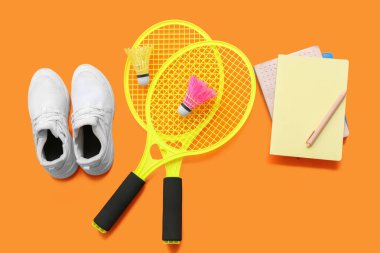 Arkaplanda badminton raketleri, mekik horozları, ayakkabılar ve kırtasiye malzemeleriyle kompozisyon