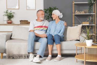 Kemoterapiden sonra olgun bir kadın ve kocası evdeki kanepede oturuyor.