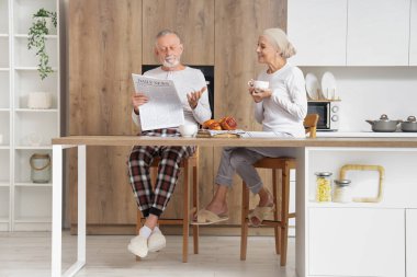 Kemoterapiden sonra olgun bir kadın kocasıyla mutfakta kahvaltı yapıyor.