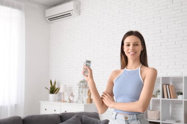Evinde klima uzaktan kumandalı güzel bir kadın.