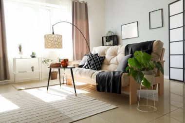 Modern oturma odasının içinde hafif kanepe, masa ve standart lamba var.