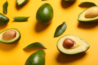 Taze olgun avokadolar ve turuncu arka planda yapraklar.