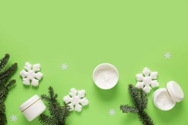 Süslü kar taneleri ve yeşil arka planda köknar dalları olan krema kavanozları.