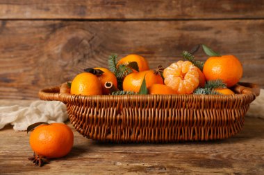 Wicker basket of sweet mandarins with cinnamon, star anise and fir branches on wooden background