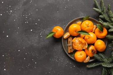 Tarçınlı tatlı mandalinalar, yıldız anasonu ve siyah arkaplanda köknar dalları