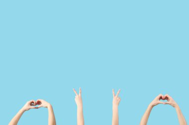 Mavi arka planda barış ve kalp jestleri gösteren kadın elleri