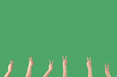 Yeşil arka planda barış jestleri gösteren kadın eller