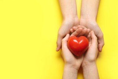 Sarı arka planda kırmızı kalpli kadın ve çocuğun elleri