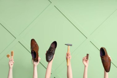 Yeşil ahşap arka planda ayakkabı, fırça ve el işi aletleri olan kadın eller. Ayakkabı tamiri kavramı