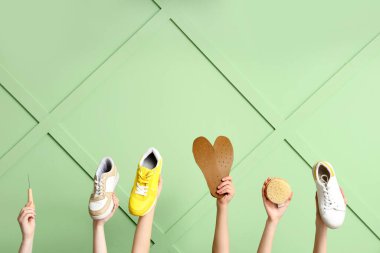 Şık spor ayakkabıları, tabanları ve yeşil ahşap arka planda fırçası olan kadın elleri. Ayakkabı tamiri kavramı