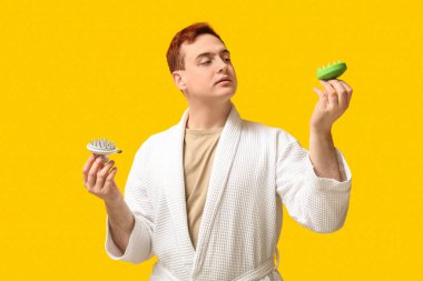 Sarı arka planda saç derisi masaj aleti olan genç bir adam.