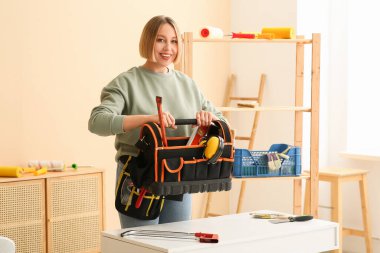 Odada alet çantası olan kadın işçi.