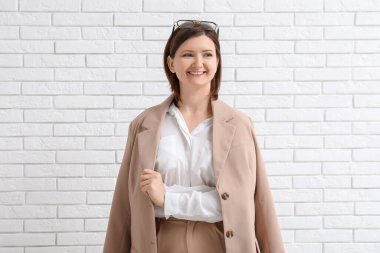 Beyaz tuğla duvarın yanında genç ve güzel bir iş kadını