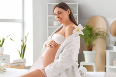 Spa salonunda çiçekli hamile bir kadın.