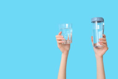 Female hands with glass and bottle of water on color background, closeup