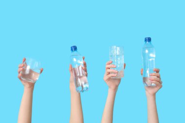 Renkli arka planda şişe ve bardak su taşıyan kadın eller, yakın plan.