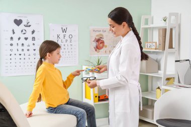 Klinikte göz doktoruyla gözlük seçen küçük bir kız.