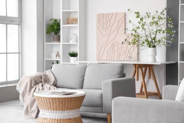 İçinde vazo ve çiçek açan dallar olan şık bir oturma odası.